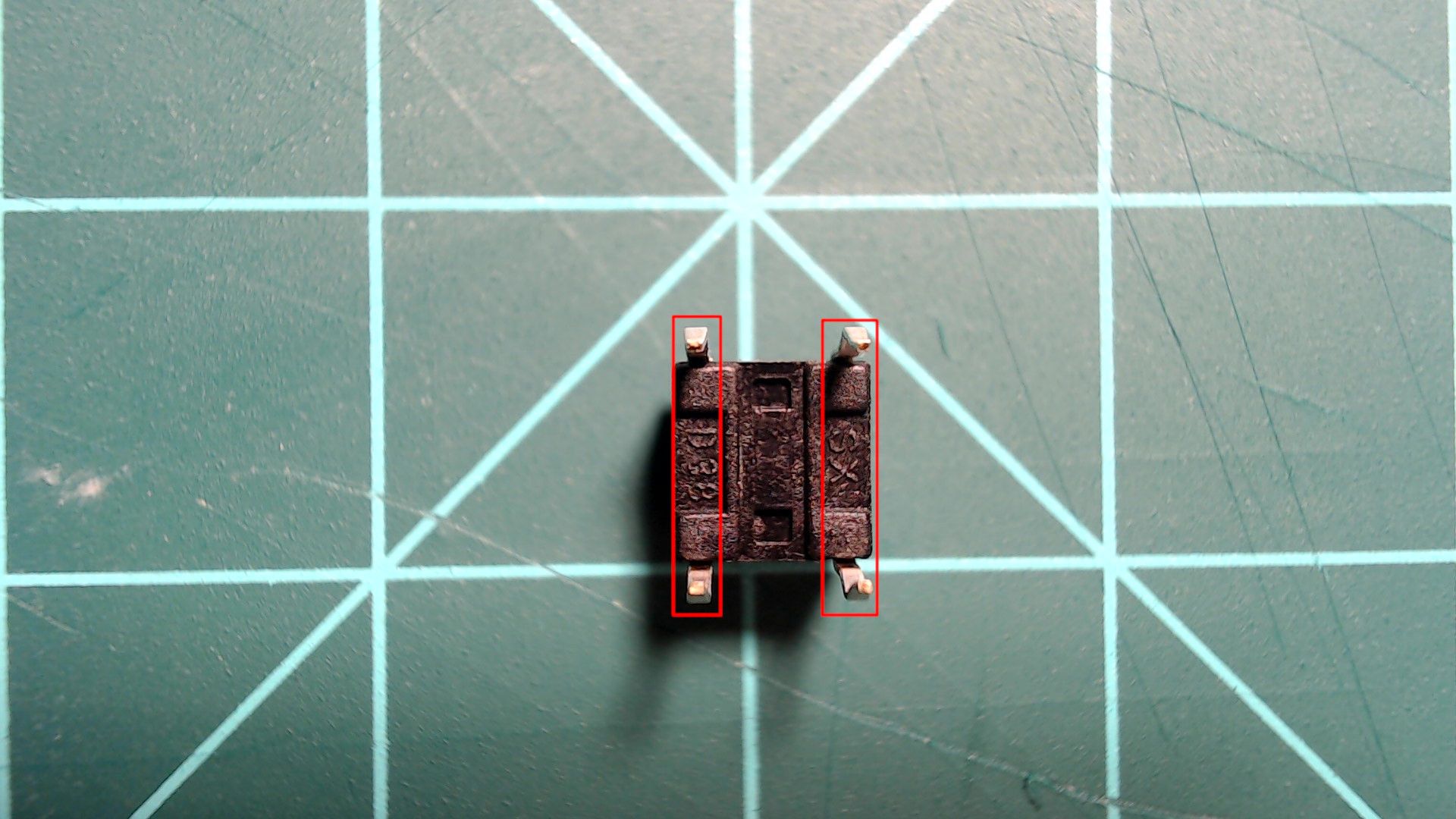 A 6 mm push button seen from above with its four legs, two at each end; red boxes pair the two legs down the left side and the two down the right side.