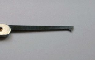 A thin metal lock pick ending in a small angled point, like half of a diamond shape, on its tip.